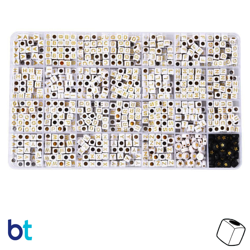 A collection of white opaque cube-shaped beads with gold lettering, displayed in a box.